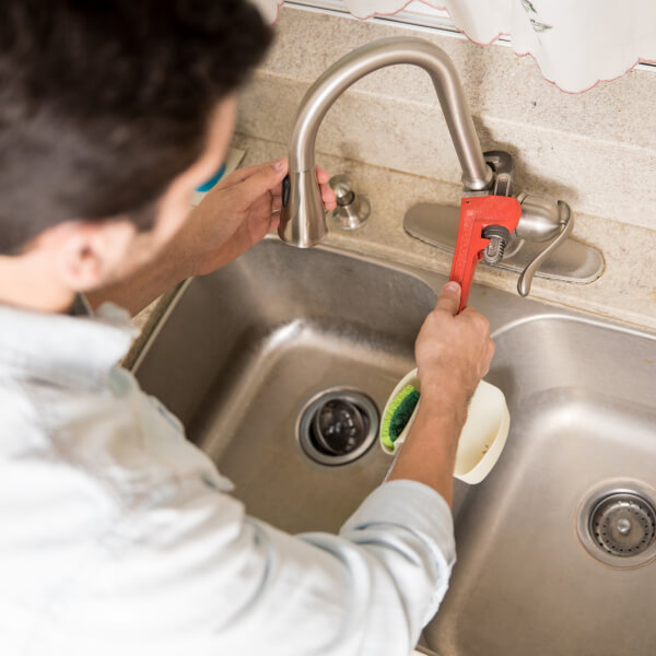 Un collage en quatre volets illustrant différents types de drains bloqués : un siphon de sol de salle de bain encrassé, un tuyau d'évier de cuisine avec des résidus alimentaires, un receveur de douche qui refoule, et une grille extérieure obstruée par des feuilles mortes.