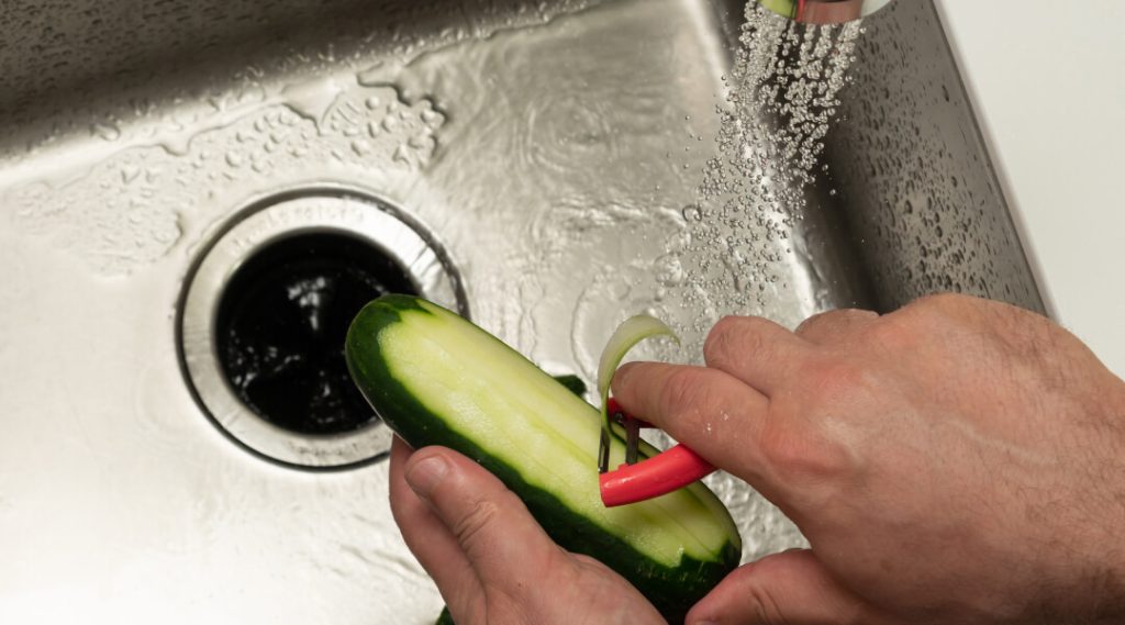 Un plan rapproché de l'eau qui s'accumule sur un parquet ou un sol stratifié moderne, illustrant le risque sérieux d'inondation domestique et de dommages matériels causés par un drain bouché.